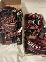Box showing multiple ratchet tie down straps, black with red edges and labels indicating 500 lbs weight capacity.
