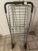 Front view of foldable shopping cart showing the aluminum frame, horizontal bars, and wheels.
