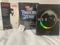 Front covers of Scarface VHS, The Twilight Zone complete 5-season DVD set, and Heroes Season 1 DVD case