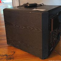 Subwoofer showing black wood grain cabinet, minor scuffs.