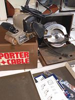 Porter Cable belt sander and Rockwell circular saw with box of jigsaw blades on floor.