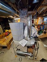 Overall view of dust collector assembly with filter cartridge, cyclone separator on stand and duct sections on floor