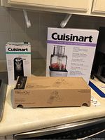 Lot of three boxed kitchen items including Cuisinart food processor, can opener, and Pampered Chef mandoline