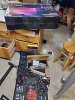 Wide view showing MSI Optix MAG321CQR curved gaming monitor box on a table with other items including the keyboard and walkie talkies on a ModMat Xtreme mat on the floor in front.