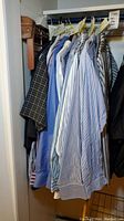 Photo showing men's dress shirts hanging on hanger rod in a closet with various colors and patterns