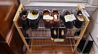 Photo showing five pairs of men's dress shoes neatly placed on the upper shelves of a wooden and metal shoe rack. Shoes include mostly size 10.5 and one size 10 pair, both black and brown leather.