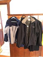 Four men's jackets hanging: Patriots reversible, Columbia, Gear for Sports, and Boss dress coat.