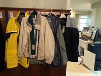 Photo showing five men's jackets hanging on a rod: yellow Kenpo jacket, beige London Fog jacket, and three gray/black jackets (Port Authority, Patagonia, West Marine).