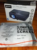 Photo of the GPX mini projector box and the simple projection screen packaging, showing product and screen size details.
