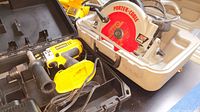 Photo showing DeWalt DC925 drill/driver with side handle and case along with Porter-Cable 7 1/4 inch circular saw in their cases.