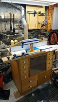 Front angle view of router table assembly on wooden cabinet with fence and glass-front storage