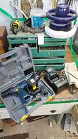 Overall view of tool box with Ryobi power drill in case, various chargers, and power buffer on top.