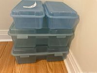 Five storage bins stacked: three larger translucent grey bins on bottom, two smaller blue bins on top, showing bin shapes and lids