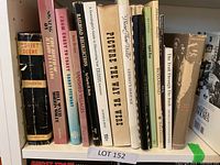 Photo of a shelf with 13 books of various genres and covers, titles visible on spines.