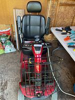 Front view of red mobility scooter showing seat, headrest, armrests, tiller and basket