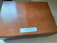 Closed wooden box with visible scratches and a label stating 'LOT 43'