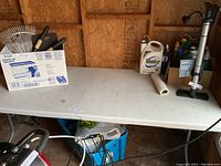 Full view of white plastic folding table with items on top (items not included). Table is rectangular, folds in half along the center crease.