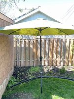 Outdoor shot of the green garden umbrella fully opened showing the canopy and pole.