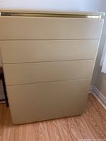 Front view of the beige Lane dresser showing all four drawers and metal accent.