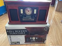 Front view of wooden turntable unit on its box showing overall design and features.