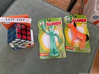 Photo of two new plastic figures in original Gumby packaging and a Rubik's Cube puzzle next to them