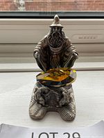 Front view of pewter wizard figurine holding large amber-colored crystal gem with base featuring two dragons.