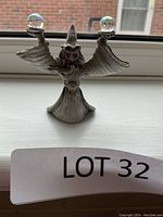 Front view of detailed pewter wizard figurine holding crystal balls, showing red eyes and outstretched arms.