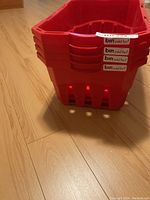 Stacked view of four red plastic shopping baskets with 'bin paid for!' stickers on handles.