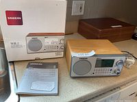 Photo showing the radio unit, its original box and instruction manual on a countertop.