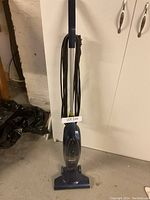 Full view of the upright Shark vacuum cleaner with power cord wrapped on back, showing slim profile and handle.