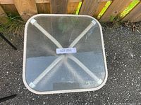 Top view of the small square garden table showing glass surface and metal frame underneath