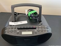 Front view of the Sony radio cassette player with handle, buttons, and digital display visible.