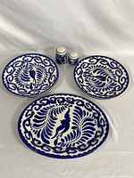 Three blue and white Anfora stoneware pieces: two plates (one serving platter oval shape 12.75 inches; one round plate 9.5 inches) and two salt and pepper shakers, all decorated with a blue foliate and bird pattern.