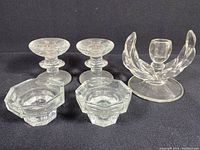 Full view of all four glass candle holders on black background, showing size and shape differences