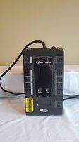 Front view of CyberPower battery backup and surge protector showing logo, power buttons, and labeled outlets.