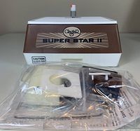 Front view of GlaStar Super Star II glass grinder in brown and white plastic housing with sealed bag of accessories
