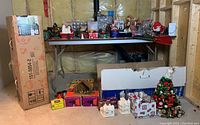 Full view of the holiday decorations laid out on and under a table including boxes and a small decorated tree ornament