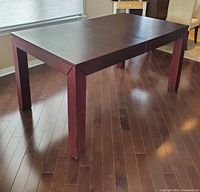 Full view of rectangular wooden kitchen table on wooden floor.