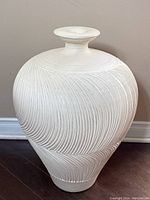 Front view of off-white ceramic lamp base with textured ribbed wave pattern and tapered shape.