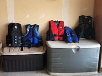 Five life jackets displayed on two storage bins