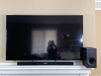 Wall-mounted TV above mantel with soundbar and subwoofer below