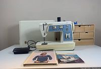 Overall view of sewing machine with foot pedal and manuals on table.