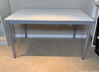 Side angle showing white wooden top and silver metal legs of table