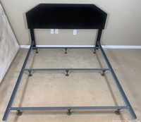 Wooden headboard with metal bed frame assembled on floor, showing overall size and condition.