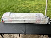 Packed and wrapped foldable frame and fabric of the tent on an outdoor table.