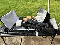 Overview of professional lighting equipment including multiple light stands, softboxes, bags, and boxes.