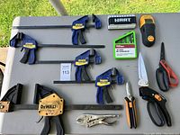 Full view of lot including clamps, stud finder, bolt extractor set, pliers, pruning shears, multi-tool, and scissors.