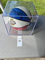 Front angled view of Spalding NBA All Star 2000 basketball in display case, showing blue, white, and red color panels and visible logos.