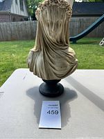 Front view of plaster bust showing floral wreath and drapery