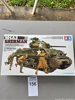 Front view of the unopened Tamiya M4A3 Sherman tank model kit box showing tank illustration and soldier figures.